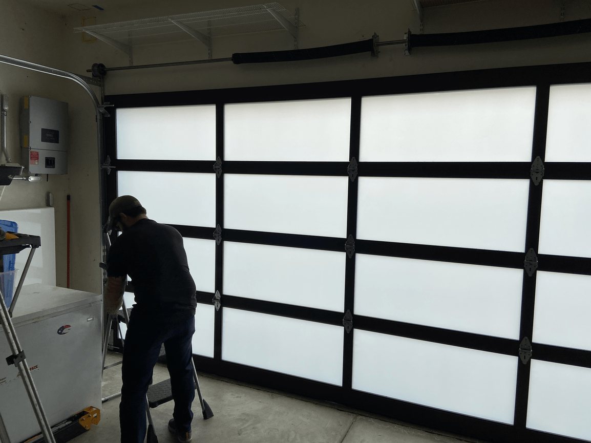 A technician working beside a full-view glass garage door